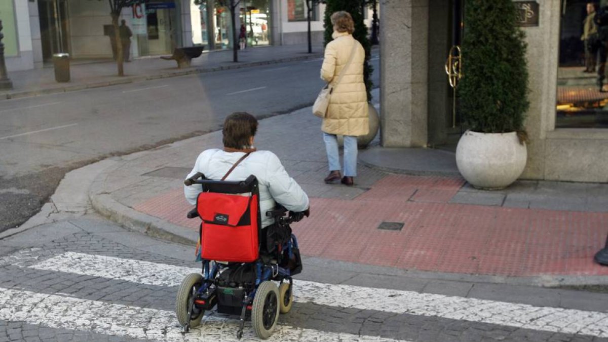 Una persona en silla de ruedas cruza un paso de cebra.-SANTI OTERO