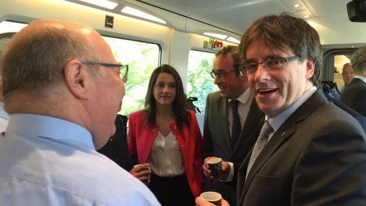 El 'president' Carles Puigdemont y la jefa de la oposición, Inés Arrimadas, junto al 'conseller' Josep Rull, en el Euromed Barcelona-Valencia.-EL PERIÓDICO