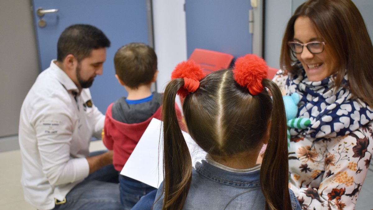 Una pareja recibe a dos niños de acogida con unos juguetes. ECB