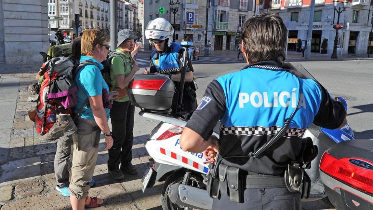 Dos agentes motorizados atienden a unos turistas en el acceso peatonal al Paseo del Espolón.-ISRAEL L. MURILLO