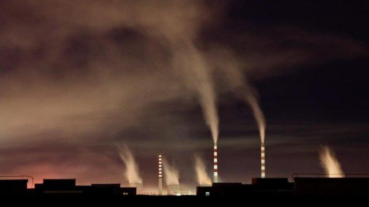 Chimeneas de una planta de energia de carbon emiten humo durante la noche en Changchun en China-