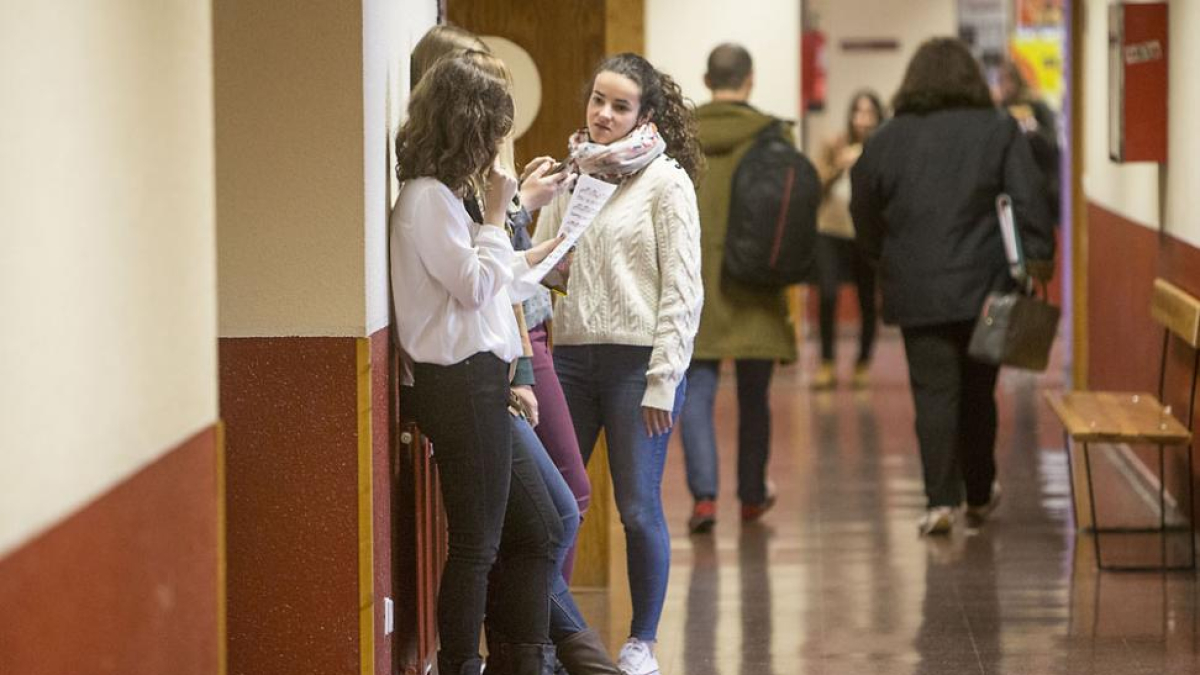 Tres estudiantes universitarias conversas en el pasillo de la Facultad de Humanidades.