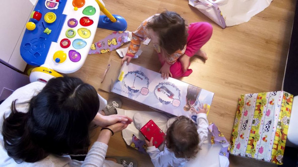 Una madre observa cómo sus hijas desempaquetan los regalos que Sus Majestades han dejado durante la noche.-SANTI OTERO