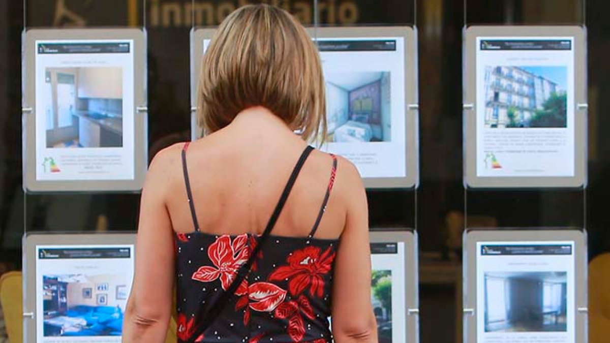 Una mujer observa anuncios de pisos en venta en el escaparate de una inmobiliaria. RAÚL G. OCHOA