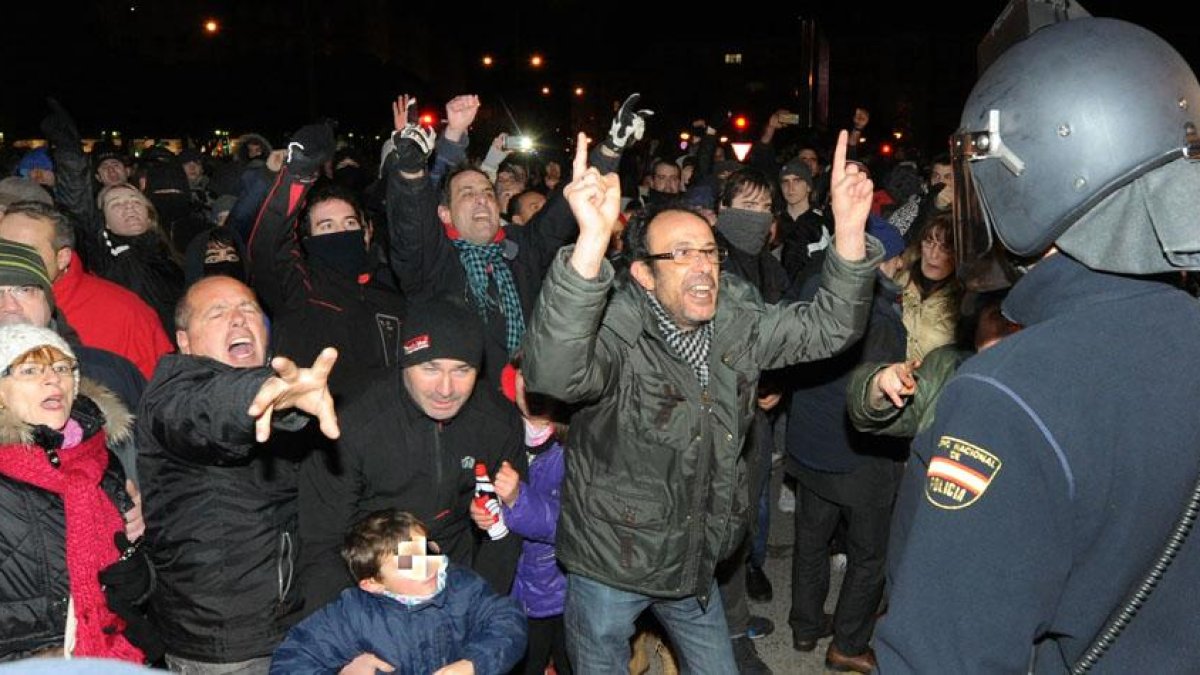 Cientos de vecinos protestan frente a un agente de la Policía Nacional.-ISRAEL L. MURILLO