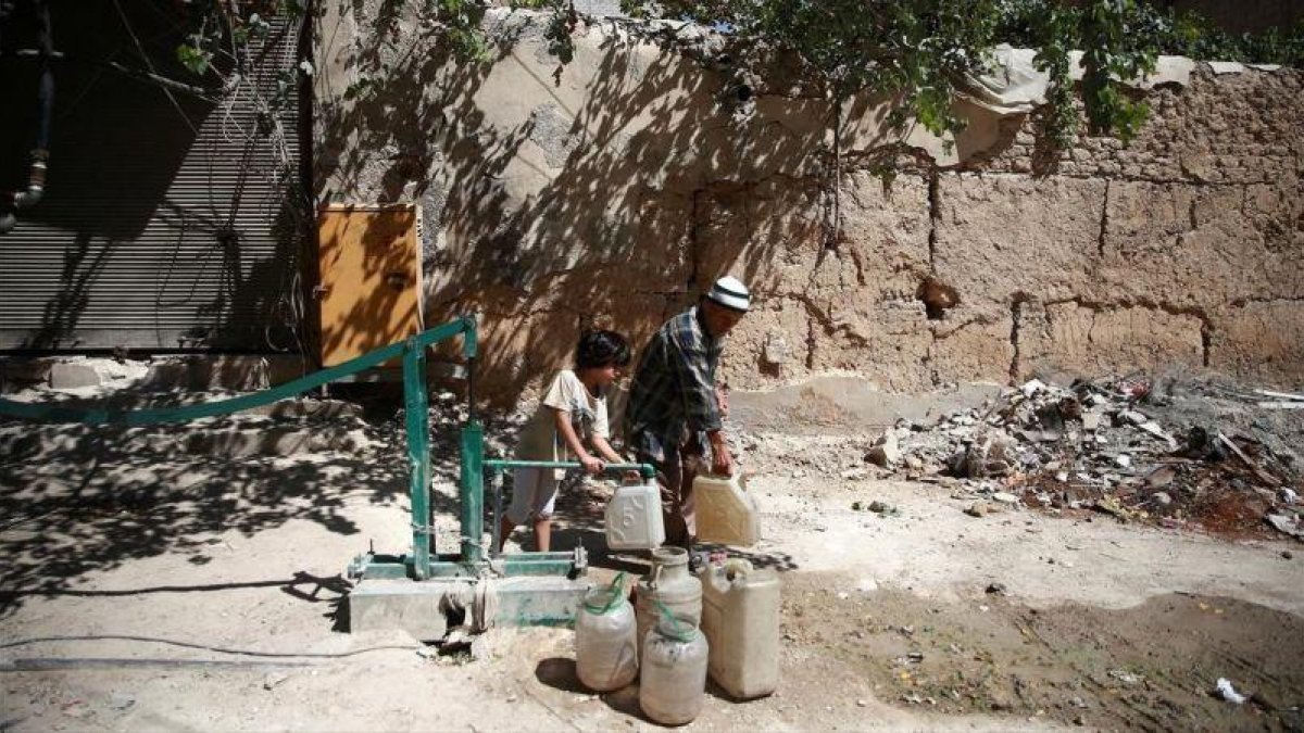 Un chico llena garrafas de agua en Damasco, Siria.-BASSAM KHABIEH