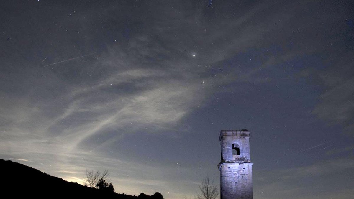 El campañario de la iglesia se recorta contra el cielo estrellado.-ICAL