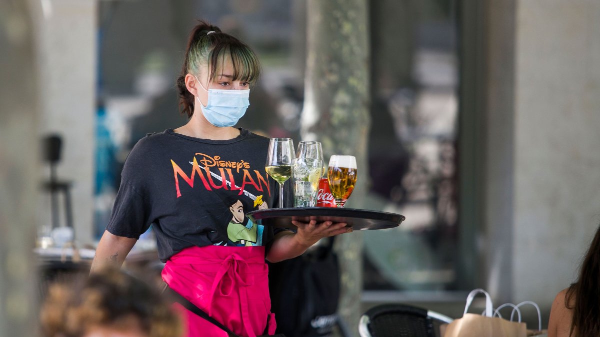 Una camarera lleva una bandeja a una  mesa en una terraza. TOMÁS ALONSO