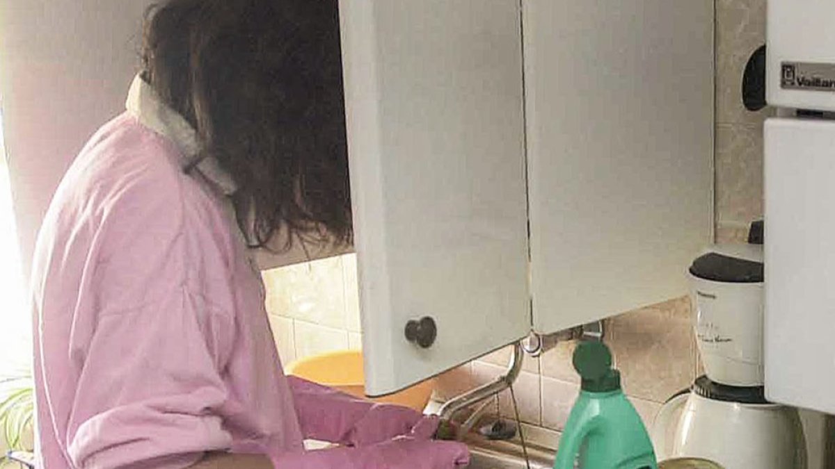 Una mujer limpia fruta en una cocina. ECB