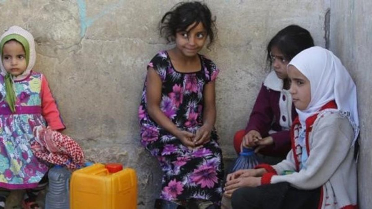 Niñas yemenís esperan para coger agua en una fuente potable en Saná.-EFE