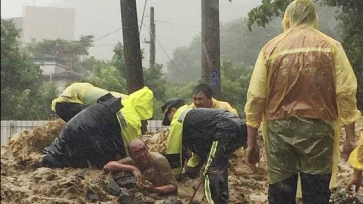 Un grupo de bomberos rescata a un hombre hundido en un charco de barro.-Foto: AP