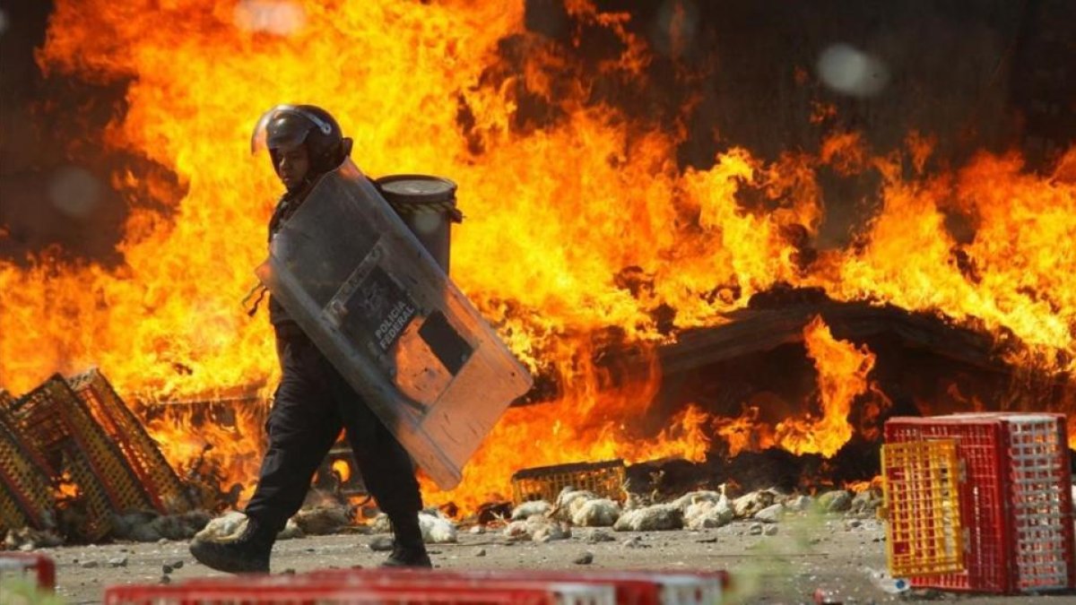 Un policía pasa frente a un camión en llamas durante las protestas contra la reforma educativa en Oaxaca.-REUTERS / JORGE LUÍS PLATA