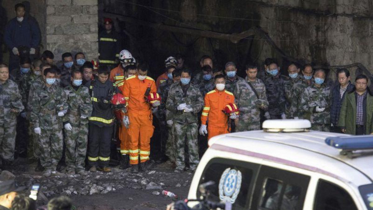 Los equipos de rescate hacen un minuto de silencio por los mineros muertos tras encontrar sus cuerpos sin vida, el martes, en la provincia de Chongqing (China)-AP / LIU CHAN
