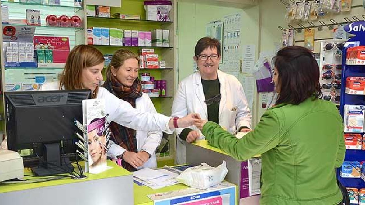 La farmacéutica Reyes Puerta (centro), atiende a una clienta junto a dos de sus empleadas en Quintanar de la Sierra.-R.F.