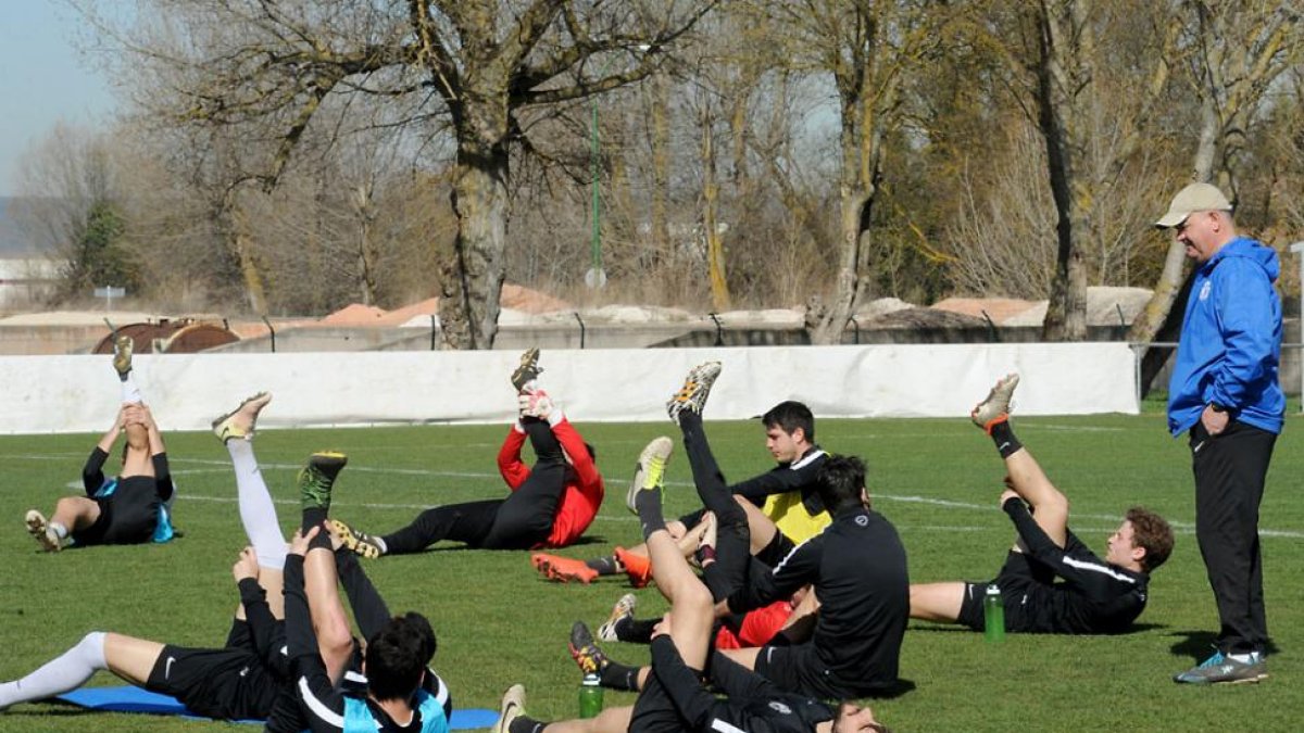 Un grupo de jugadores del Burgos CF realizan estiramientos ante la atenta mirada de Mandiola-I. L. Murillo