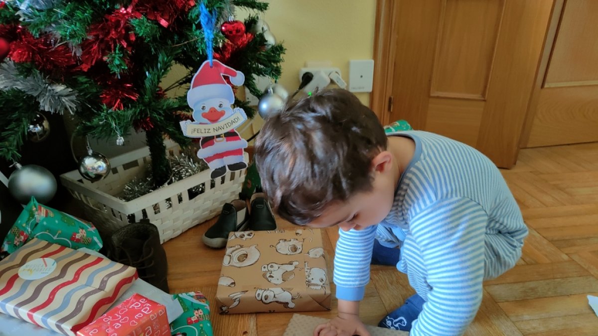 Un niño recién levantado abre sus regalos en la mañana de Reyes. ECB