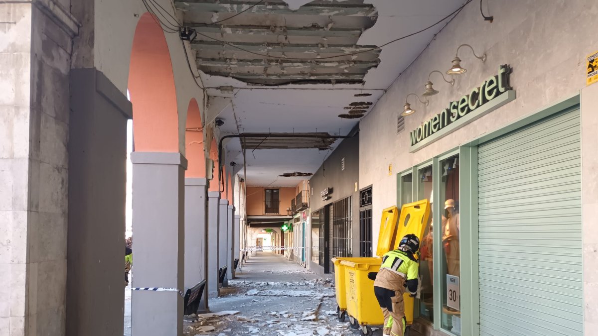 Un bombero recoge restos del techo caído en los soportales de la Plaza Mayor de Aranda. ECB
