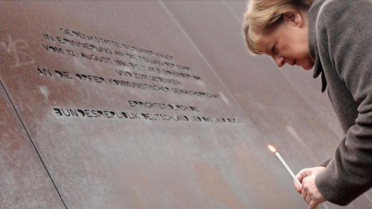La canciller alemana coloca una vela en el Memorial del Muro de Berlín.-AFP / TOBIAS SCHWARZ