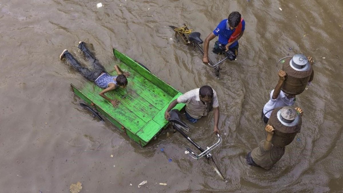 Lecheros intentan abrirse paso por una calle inundada tras las fuertes lluvias en Allahabad, India. /-RAJESH KUMAR SINGH (AP)