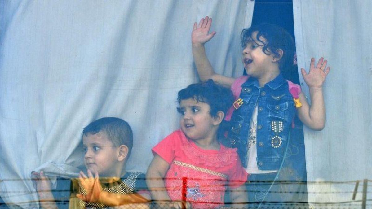 Niños refugiados sirios miran a través de la ventana de un autobús antes de abandonar Beirut este domingo de regreso a sus hogares en Siria.-EFE / WAEL HAMZEH
