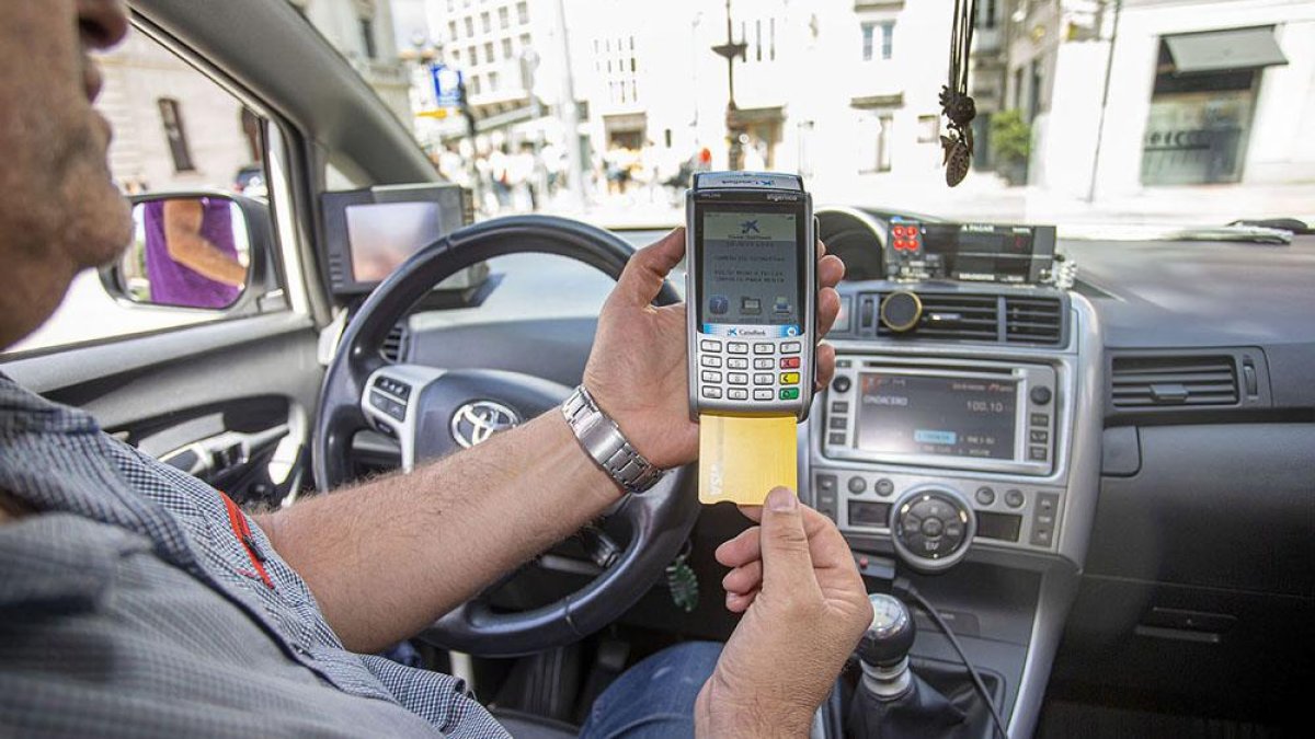 Un taxista ejecuta un cobro con tarjeta con el datáfono.-SANTI OTERO