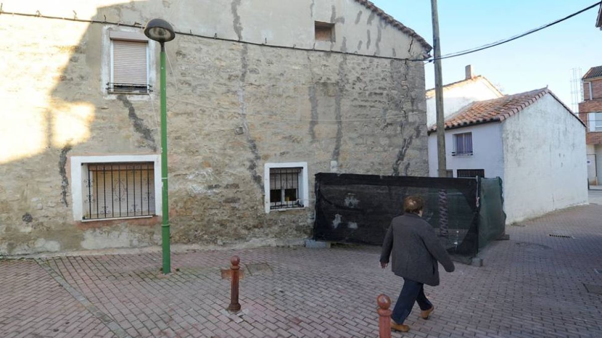 Una vecina pasa por delante de una de las casas donde se ve claramente el deterioro por las grietas.-ISRAEL L. MURILLO