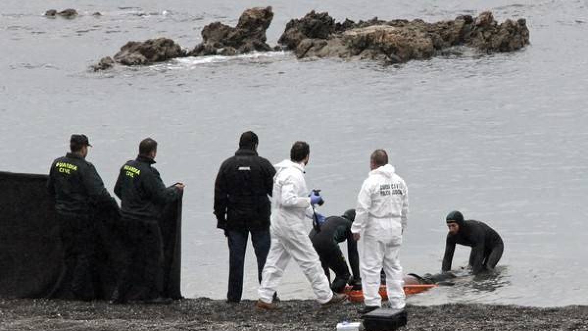 Agentes de la Guardia Civil retiran el cuerpo del subsahariano encontrado hoy en la playa del Tarajal de Ceuta.-Foto: EFE / REDUAN DRIS REGRAGUI