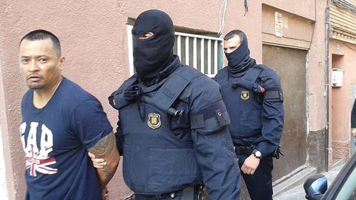 Imagen cedida por la Cadena Ser, en la que dos mossos se llevan detenido, en Santa Coloma de Gramenet, a uno de los presuntos miembros de la banda de Latin Kings desarticulada este miércoles.-Foto: CADENA SER