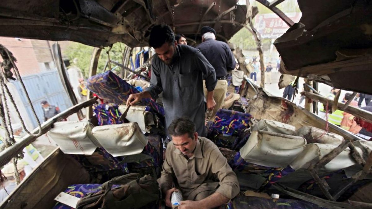 Miembros de las Fuerzas de Seguridad inspeccionan un autobús que ha sufrido un atetado con bomba en Peshawar.-EFE / BILAWAL ARBAB