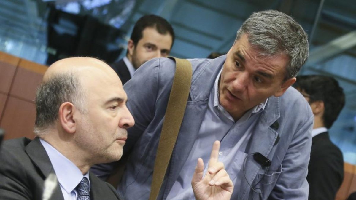 El comisario de Asuntos Económica, Pierre Moscovici (izqueirda), habla con el ministro griego de Finanzas, Euclides Tsakalotos, el martes en Bruselas.-EFE / OLIVIER HOSLET