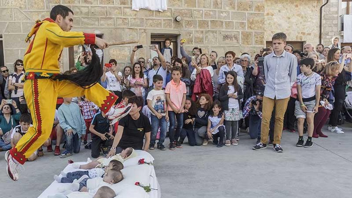 El Colacho salta sobre uno de los colchones bajo la inocente mirada de los bebés, ajenos a todo lo que estaba sucediendo a su alrededor.-SANTI OTERO