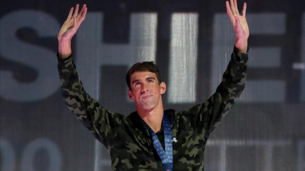 Phelps saluda desde el podio tras conquistar el triunfo en los 100 mariposa-TOM PENNINGTON / AFP