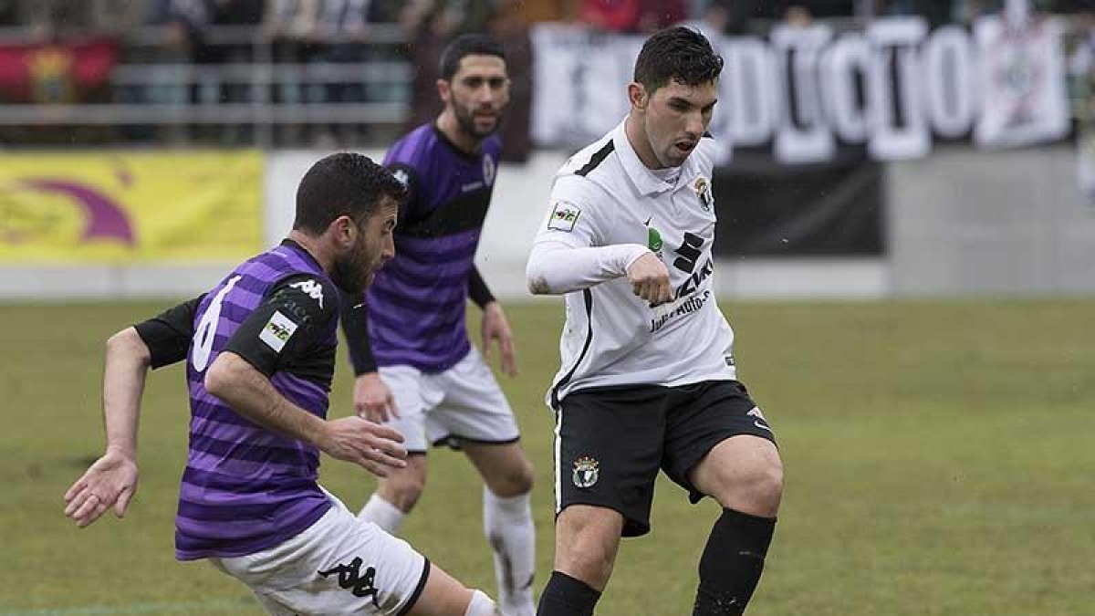 Carlos Ramos intenta el pase ante la presión de un jugador del Palencia.-JARCHA-BURGOSDEPORTE.COM