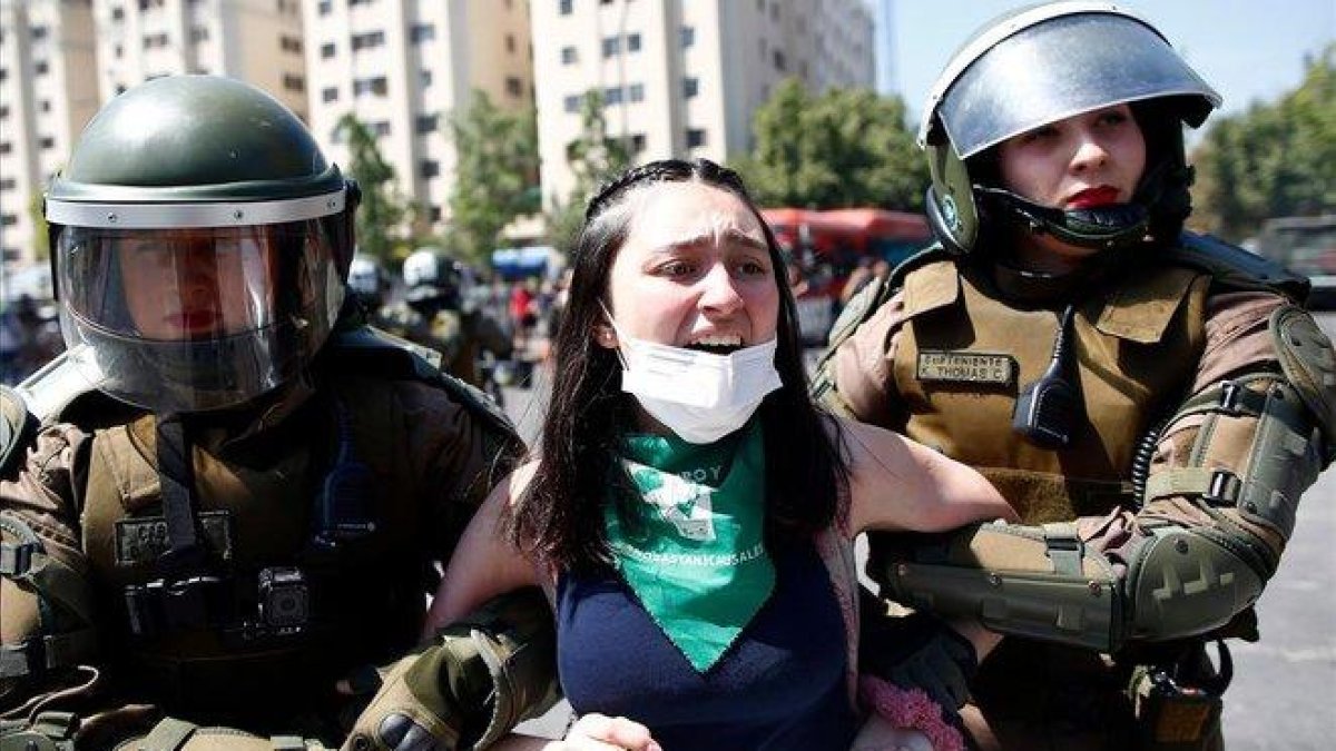 Dos agentes antidisturbios detienen a una joven manifestante en Santiago de Chile.-PABLO VERA (AFP)