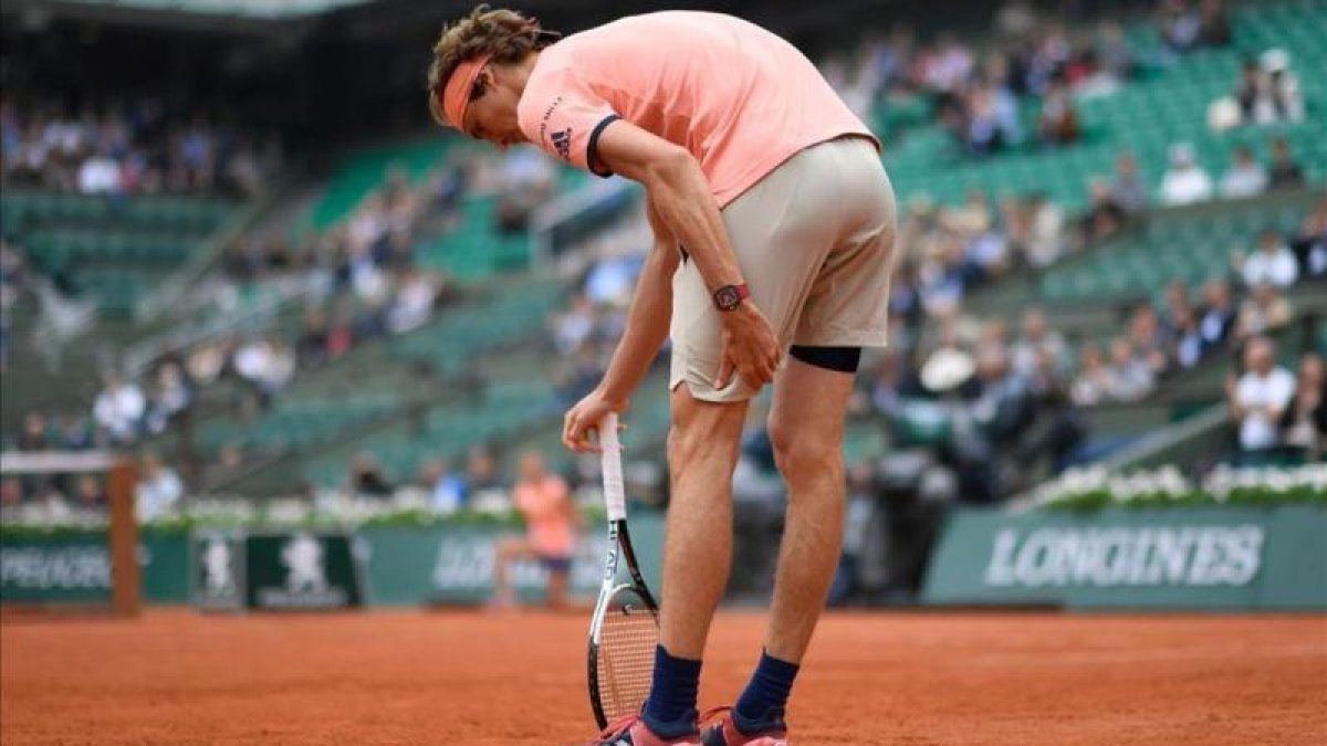 Alexander Zverev, se toca su pierna izquierda, ayer durante el partido ante Thiem.-AFP / CHRISTOPHE SIMON