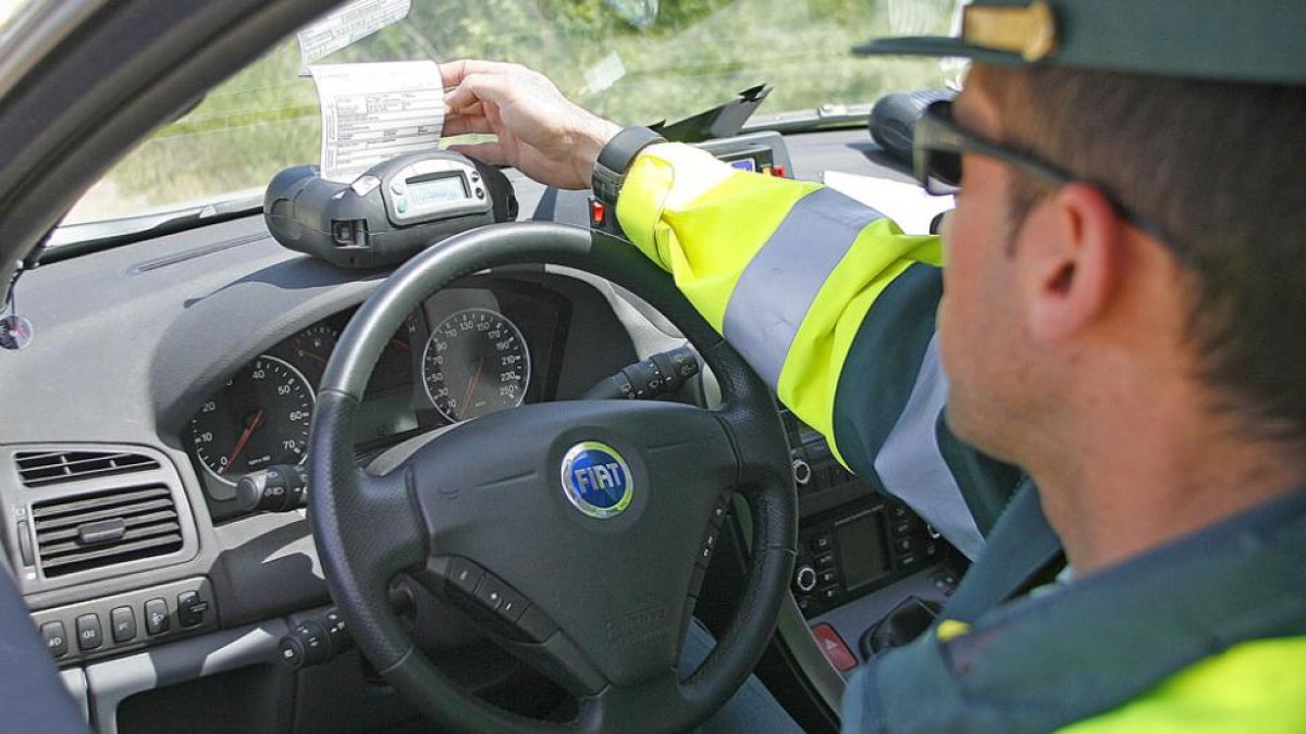 Un agente imprime una multa desde un vehículo en un control en carretera.-ISRAEL L. MURILLO