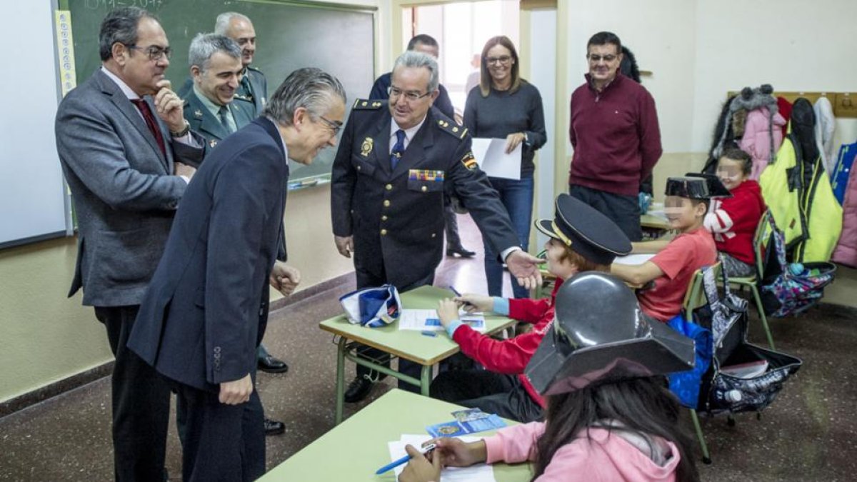 El subdelgado, el delegado territorial y mandos policiales saludan a los niños en una clase.-ISRAEL L. MURILLO