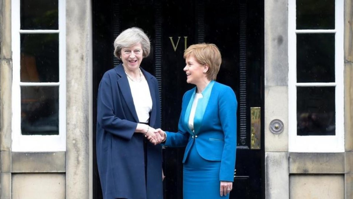 May (izquierda) y Sturgeon se dan la mano en la puerta de Bute House, en Edimburgo, este viernes.-AFP / LESLEY MARTIN