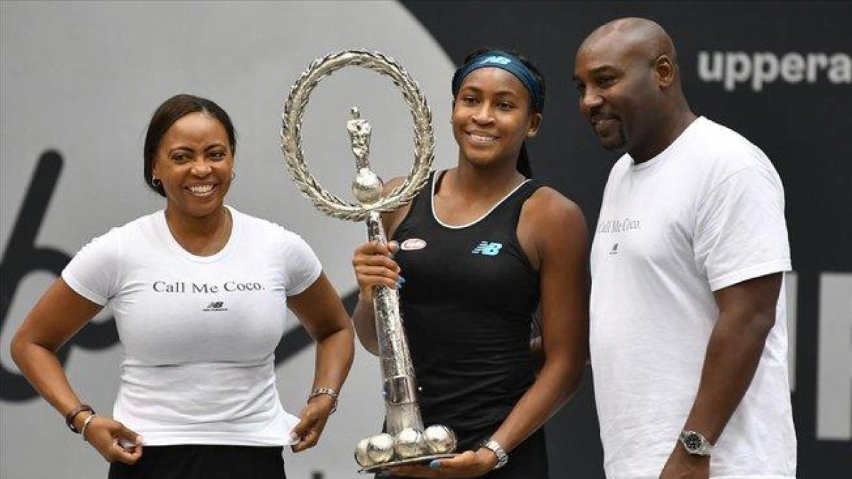 Gauff muestra feliz su primer trofeo junto a sus padres, en Linz.-