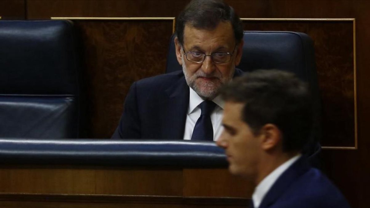 El presidente del Gobierno, Mariano Rajoy, en una sesión parlamentaria observa el paso del líder de Cs, Albert Rivera.-AGUSTÍN CATALÁN