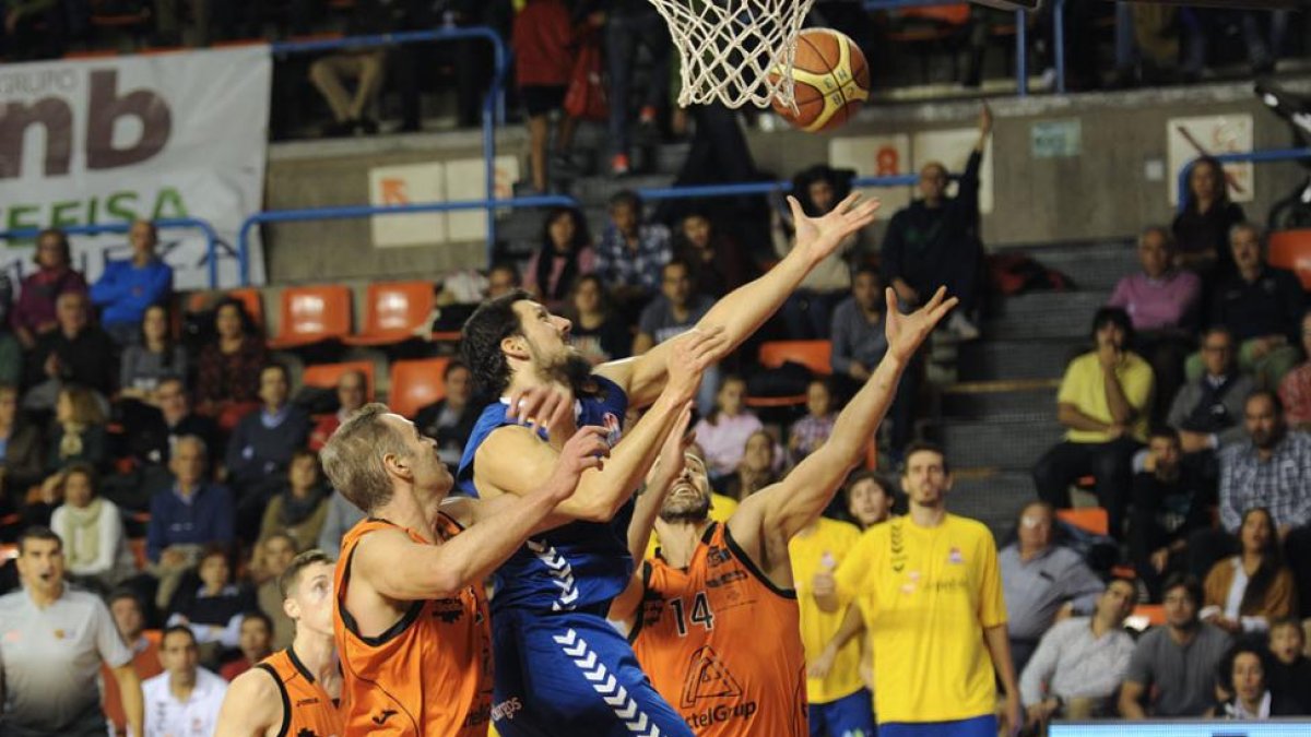 Poscic lanza a canasta ante la oposición de los jugadores del Lleida Jorge García y Alzamora.-ISRAEL L. MURILLO