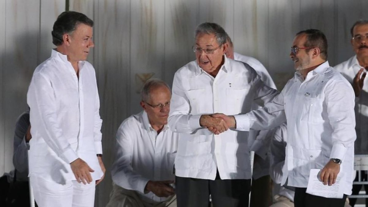 Raúl Castro, presidente de Cuba (centro) da la mano al comandante jefe de las FARC, Rodrigo Londoño, en presencia del presidente de Colombia, Juan Manuel Santos, en Cartagena de Indias, el 26 de septiembre.-AP / FERNANDO VERGARA