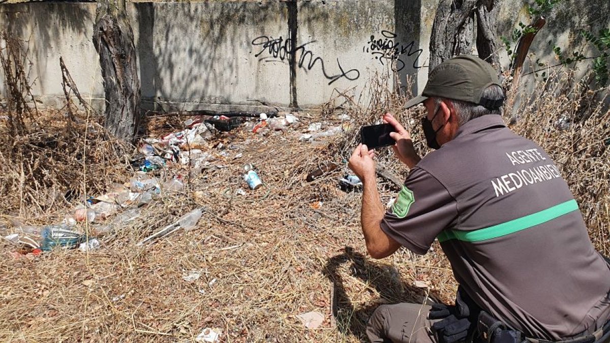 Un agente medioambiental documenta los daños en una zona de botellón pegada al parque Virgen Viñas. L. V.