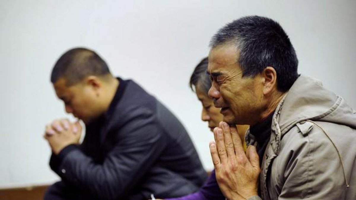 Familiares de los pasajeros del vuelo de Malaysia Airlines rezan, en un hotel de Pekín.-AFP / WANG ZHAO