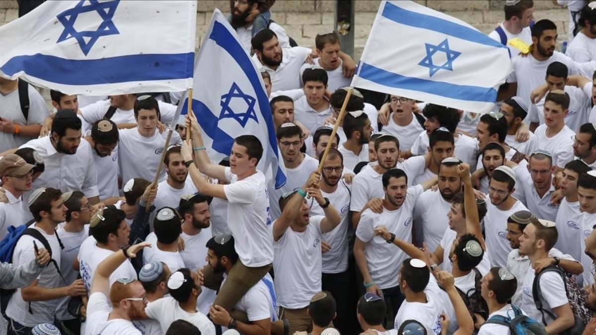 Manifestantes israelís celebran la aprobación de la ley en el Parlamento. /-AP / ARIEL SCHALIT