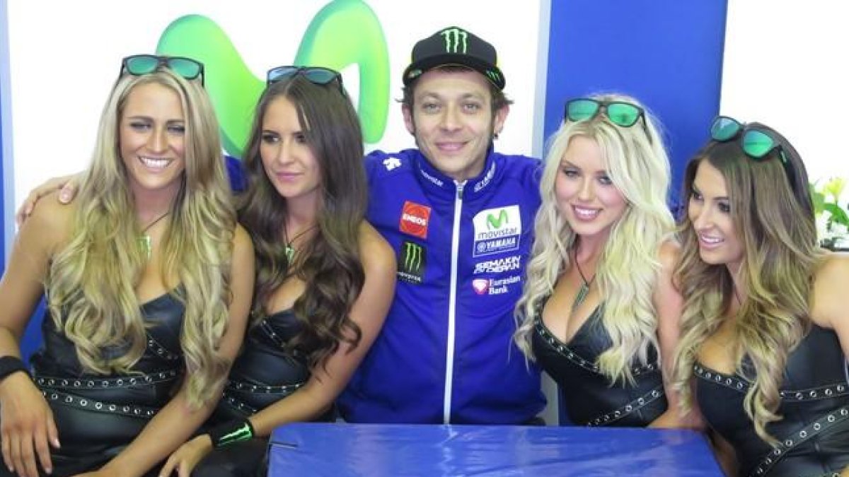 Valentino Rossi y cuatro chicas de Monster, su patrocinador personal, en la improvisada sala de prensa del Movistar Yamaha.-EMILIO PÉREZ DE ROZAS