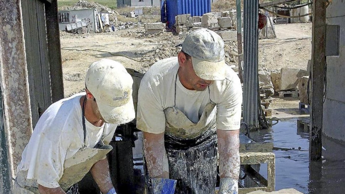 Dos operarios mueven placas de piedra en Villamayor-Ical