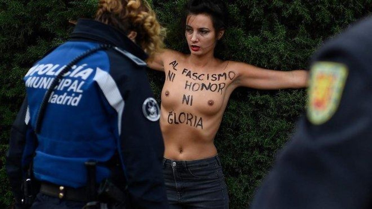 Un agente policial retiene a una activista de Femen, este domingo, en la Plaza de Oriente de Madrid.-AFP / ÓSCAR DEL POZO