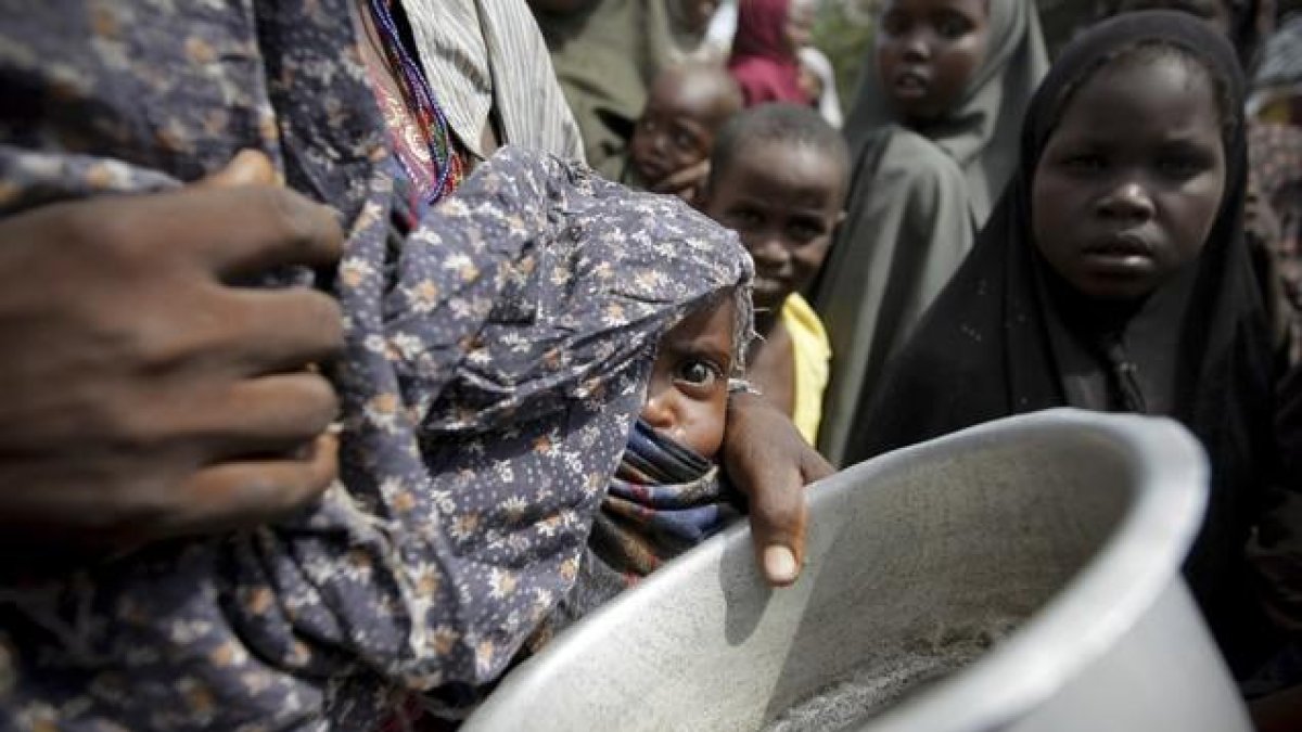 Una mujer con su bebé mientras hace cola para conseguir alimentos en un campamento para los desplazados de Mogadiscio (Somalia)-REUTERS