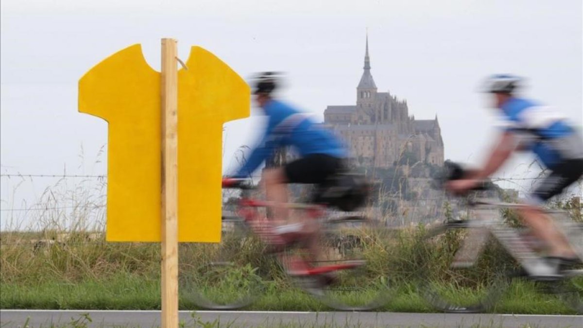 Uno ciclistas pasan cerca del Mont de Saint Michel, donde el sábado comienza el Tour.-AFP / KENZO TRIBOUILLARD